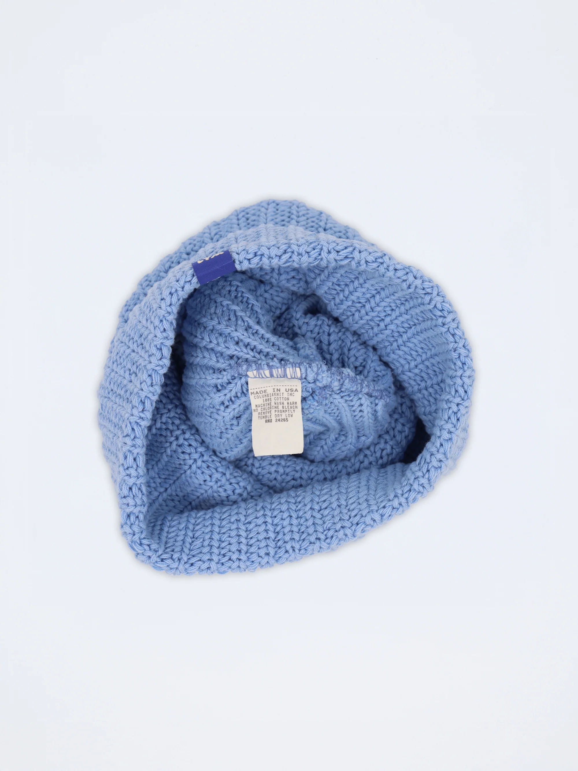 A soft blue Essentials beanie turned inside out, care label showing