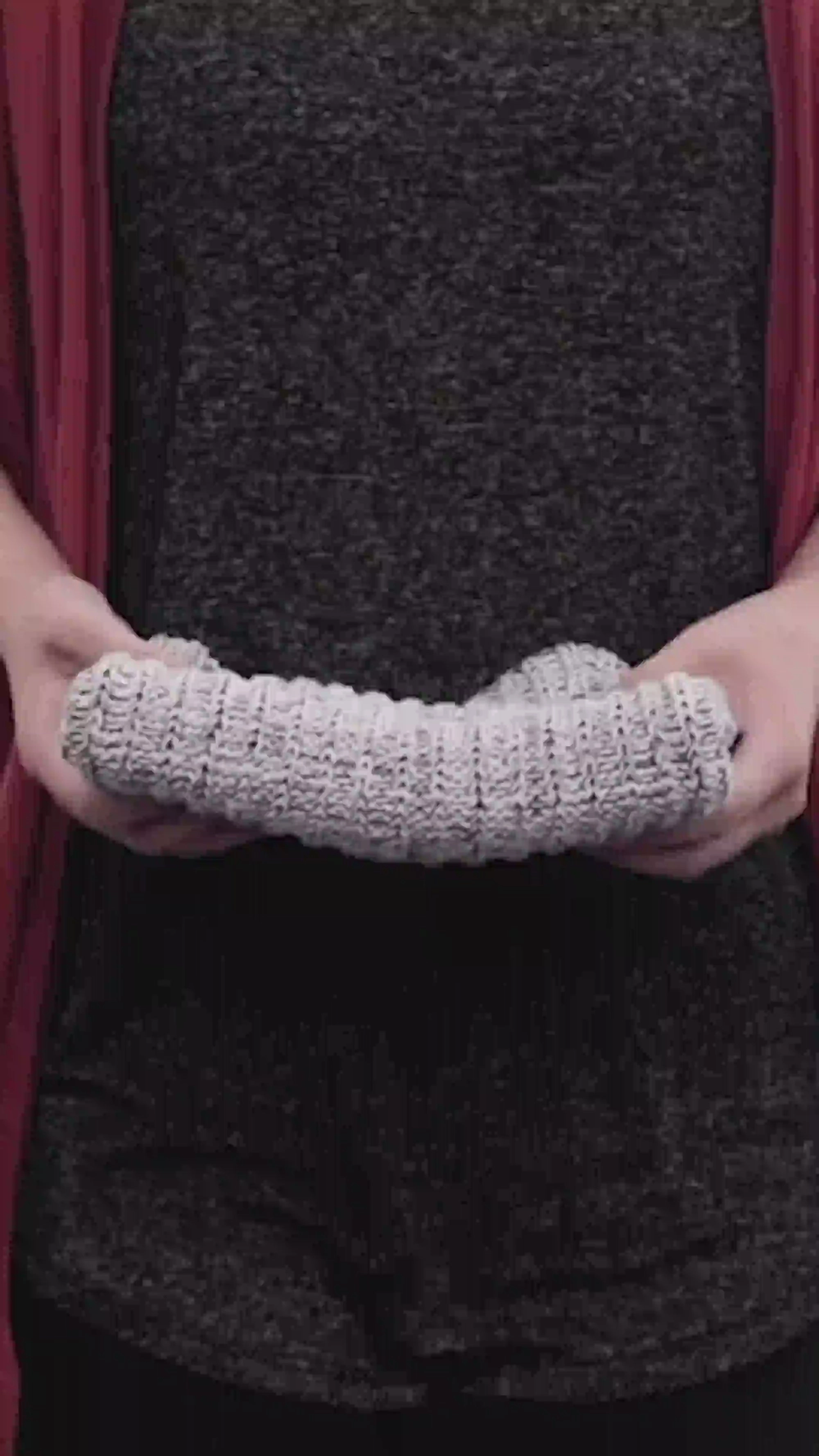 Two hands holding out a folded knit beanie